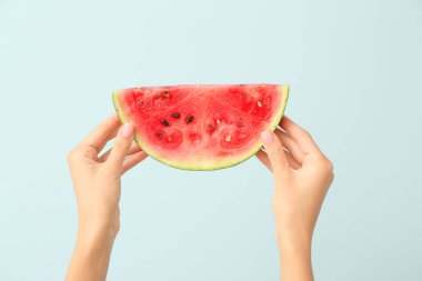 Renkli arka planda sulu karpuz parçasıyla kadın elleri