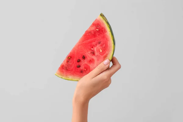 Weibliche Hand mit einem Stück saftige Wassermelone auf hellem Hintergrund — Stockfoto