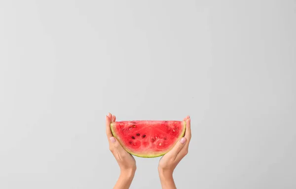 Weibliche Hände mit einem Stück saftige Wassermelone auf hellem Hintergrund — Stockfoto