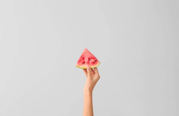 Female hand with piece of juicy watermelon on light background — Stock Photo, Image