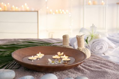 Güzellik merkezinde havluda su, mum ve spa malzemeleri var.