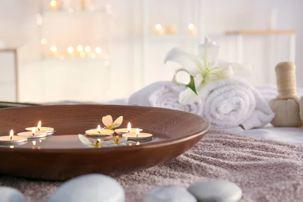 Plate with water and candles on towel in beauty center — Stock Photo, Image