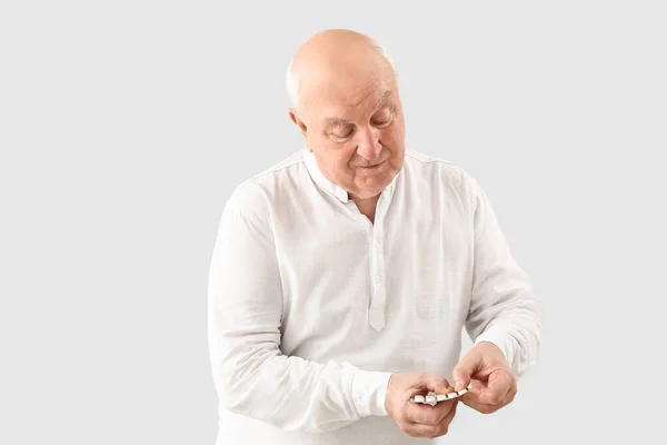 Hombre de edad avanzada con pastillas sobre fondo claro — Foto de Stock