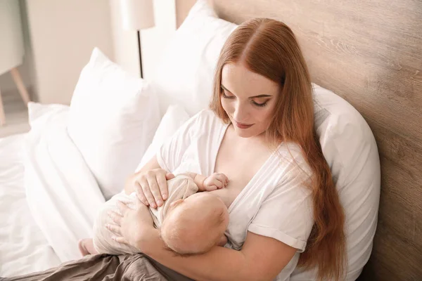 Jovem mulher amamentando seu bebê em casa — Fotografia de Stock