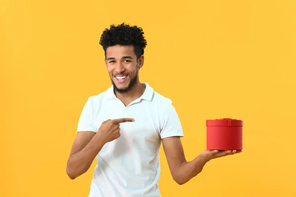 Retrato del hombre afroamericano feliz con regalo sobre fondo de color — Foto de Stock