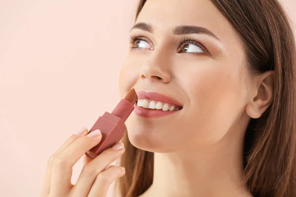 Vacker ung kvinna med läppstift på färg bakgrund — Stockfoto