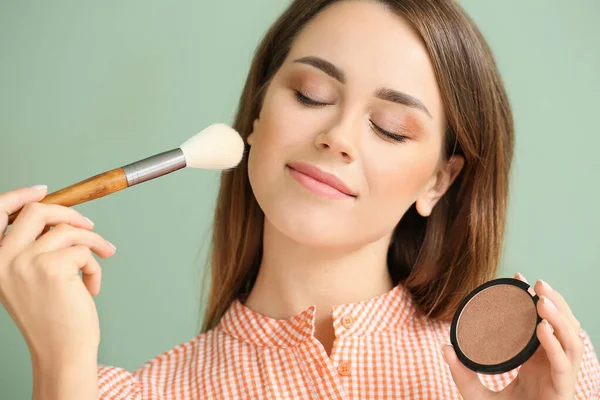 Vacker ung kvinna med makeup borste och pulver på färg bakgrund — Stockfoto