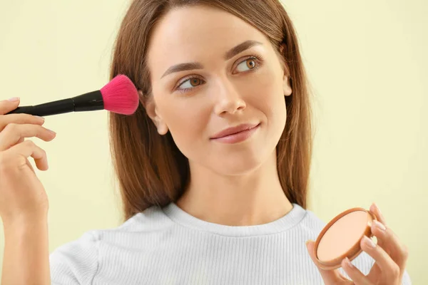 Beautiful young woman with makeup brush and powder on color background — Stock Photo, Image