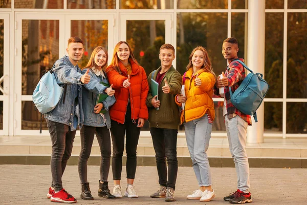 Grupo de estudiantes adolescentes mostrando pulgar hacia arriba cerca de la universidad — Foto de Stock