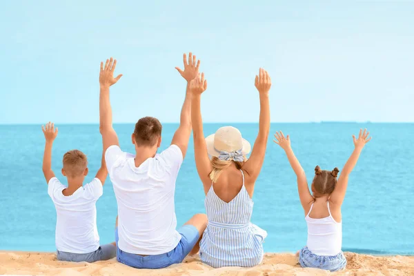Familia feliz sentado en la playa del mar —  Fotos de Stock