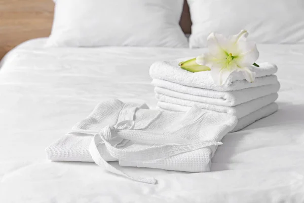 Мягкий чистый халат и полотенца на кровати — стоковое фото