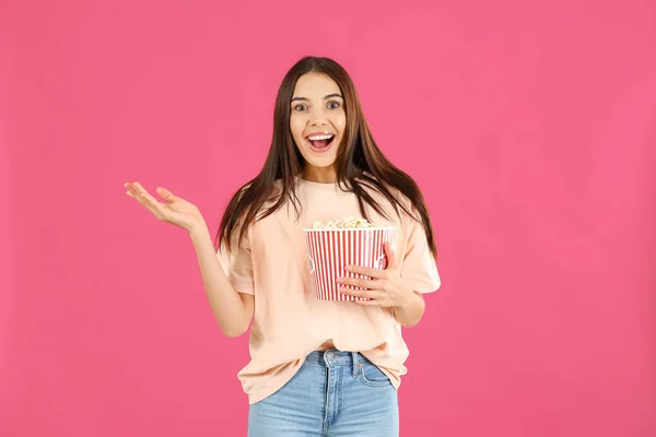Surprised woman with popcorn on color background — ストック写真