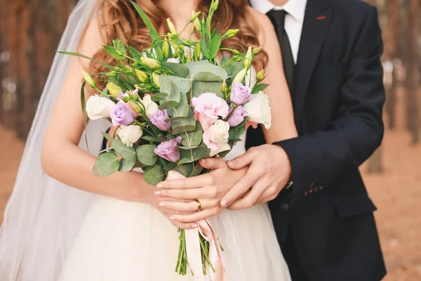 Happy wedding couple with bouquet of flowers outdoors — ストック写真