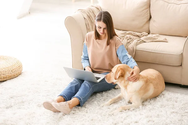 Beautiful young woman with cute dog using laptop at home — Stock Photo, Image