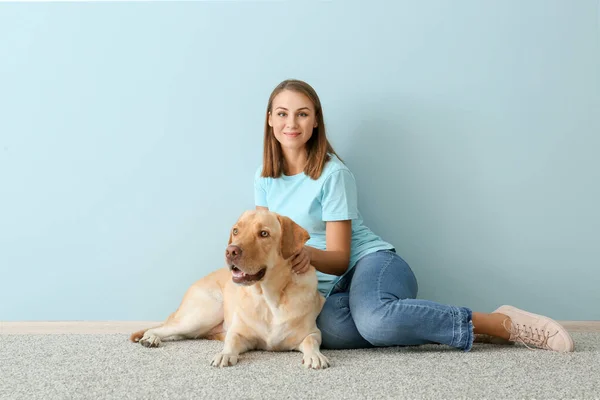 Vacker ung kvinna med söt hund nära färg vägg — Stockfoto