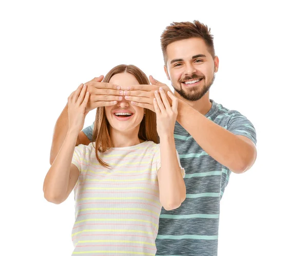 Happy man covering eyes of his girlfriend on white background — Stockfoto