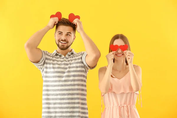 Retrato de feliz pareja joven con corazones de papel sobre fondo de color — Foto de Stock