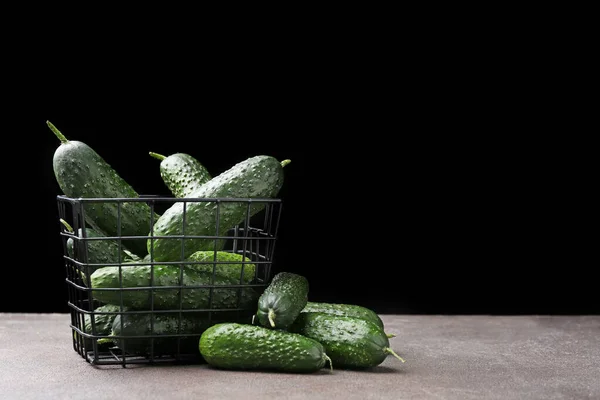 Basket with fresh green cucumbers on table against dark background — Stock Photo, Image