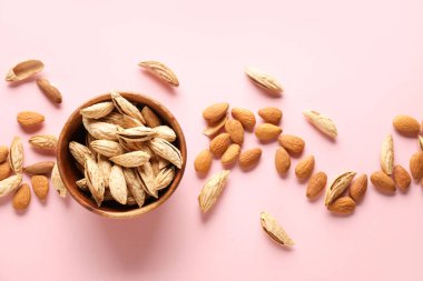 Renkli arkaplanda lezzetli bademler olan kase