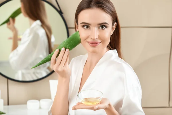 Beautiful young woman using aloe vera in bathroom — Stock Photo, Image