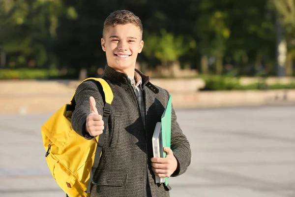 Portrét dospívajícího studenta ukazující palec nahoru venku — Stock fotografie