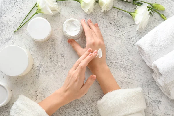 Young woman applying hand cream at table — Stock Photo, Image