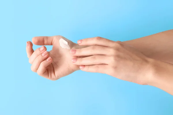 Young woman applying hand cream on color background — Stock Photo, Image