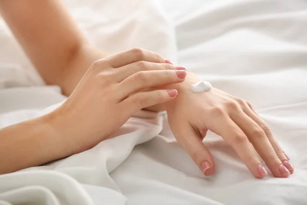 Jovem aplicando creme em suas mãos, close-up — Fotografia de Stock