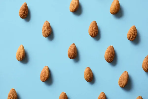 Many tasty almonds on color background — Stock Photo, Image