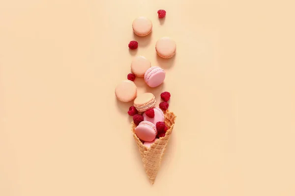 Wafer cone with tasty macarons and raspberry on color background — Stock Photo, Image