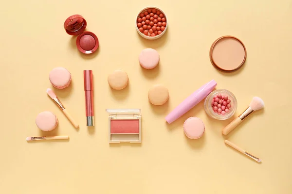 Macarons savoureux avec cosmétiques de maquillage sur fond de couleur — Photo