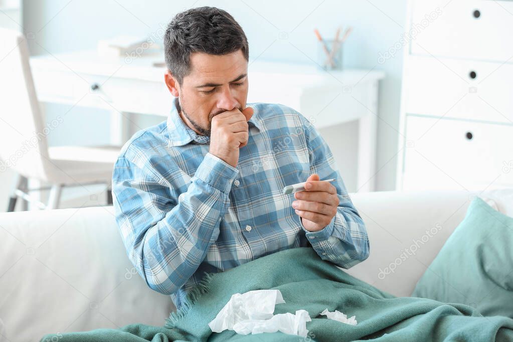 Man ill with flu measuring temperature at home