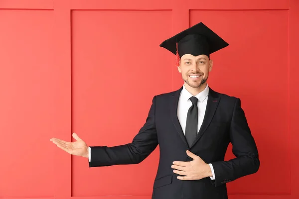 Uomo Cappello Laurea Mostrando Qualcosa Sullo Sfondo Colore — Foto Stock