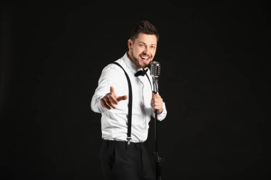 Yakışıklı adam karanlık arka planda şarkı söylüyor.