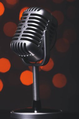 Koyu arkaplanda bulanık ışıkları olan bir mikrofon