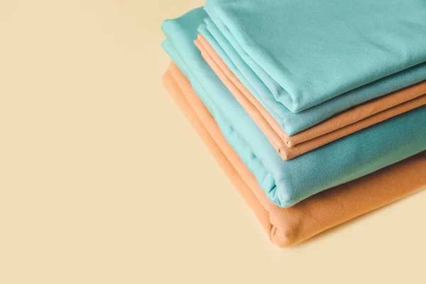 Stack of clean bed sheets on color background