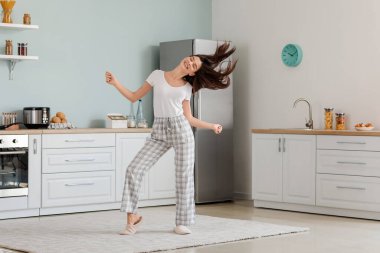 Güzel genç bayan mutfakta dans ediyor.