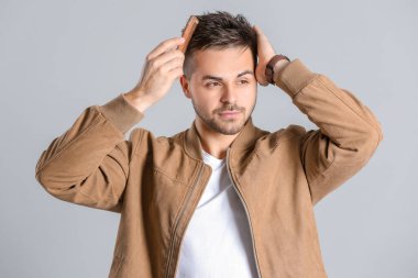 Güzel saç stili ve gri arka planı olan yakışıklı bir adam.
