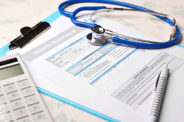 Işık arka planında steteskop ve hesap makineli sağlık sigortası formu