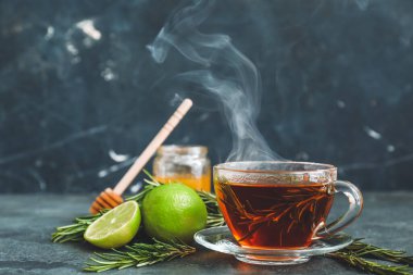 Siyah arka planda biberiyeli bir fincan sıcak çay.