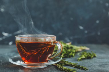 Siyah arka planda biberiyeli bir fincan sıcak çay.