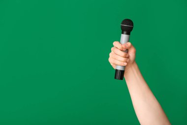 Renkli arka planda mikrofonu olan genç adamın eli