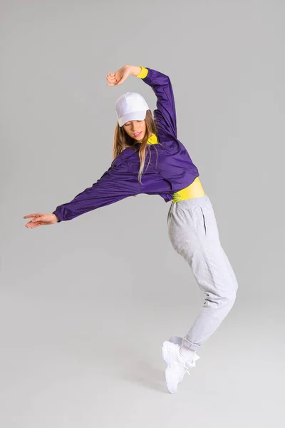 Young female hip-hop dancer on grey background