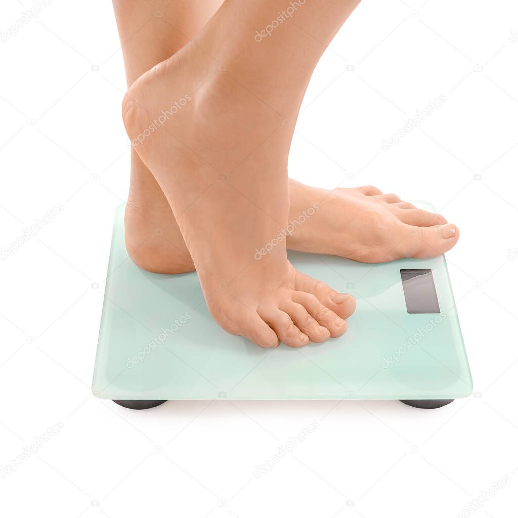 Young woman measuring her weight on white background