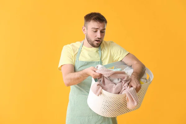 Troubled man with laundry on color background