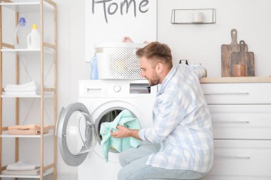 Genç adam evde çamaşır yıkıyor.