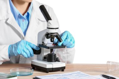Beyaz arkaplana karşı mikroskopla çalışan bilim adamı