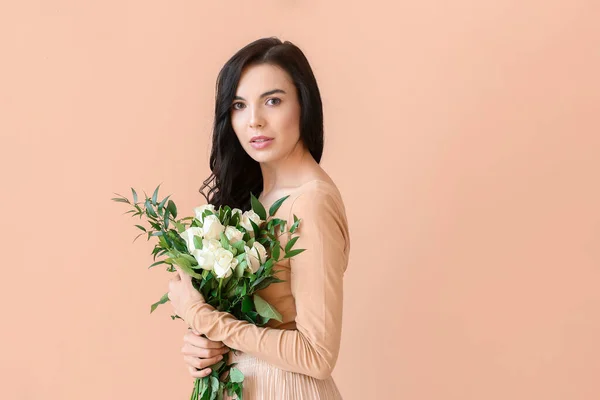 Beautiful young woman with bouquet of roses on color background