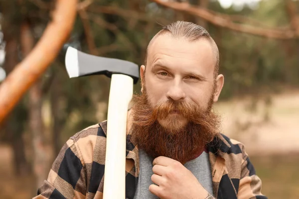 Ormanda baltayla dolaşan yakışıklı bir oduncu.