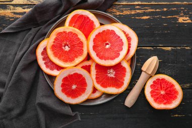 Koyu ahşap zemin üzerinde taze kesilmiş greyfurt tabağı.